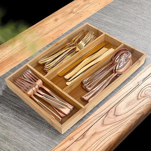 Portaposate da cassetto in bambù con quattro scomparti e posate dorate su un tavolo di legno