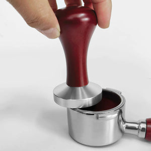 Pressino caffè con manico in legno premuto in un portafiltro con il caffè