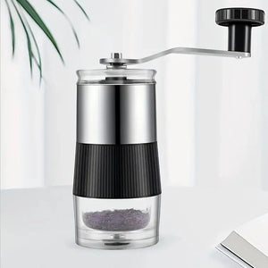 Macinacaffè manuale con parte superiore in acciaio, impugnatura nera zigrinata, contenitore trasparente e manovella con pomello nero