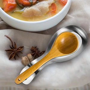 Poggiamestolo in acciaio inox con un cucchiaio di legno accanto a una ciotola di minestra