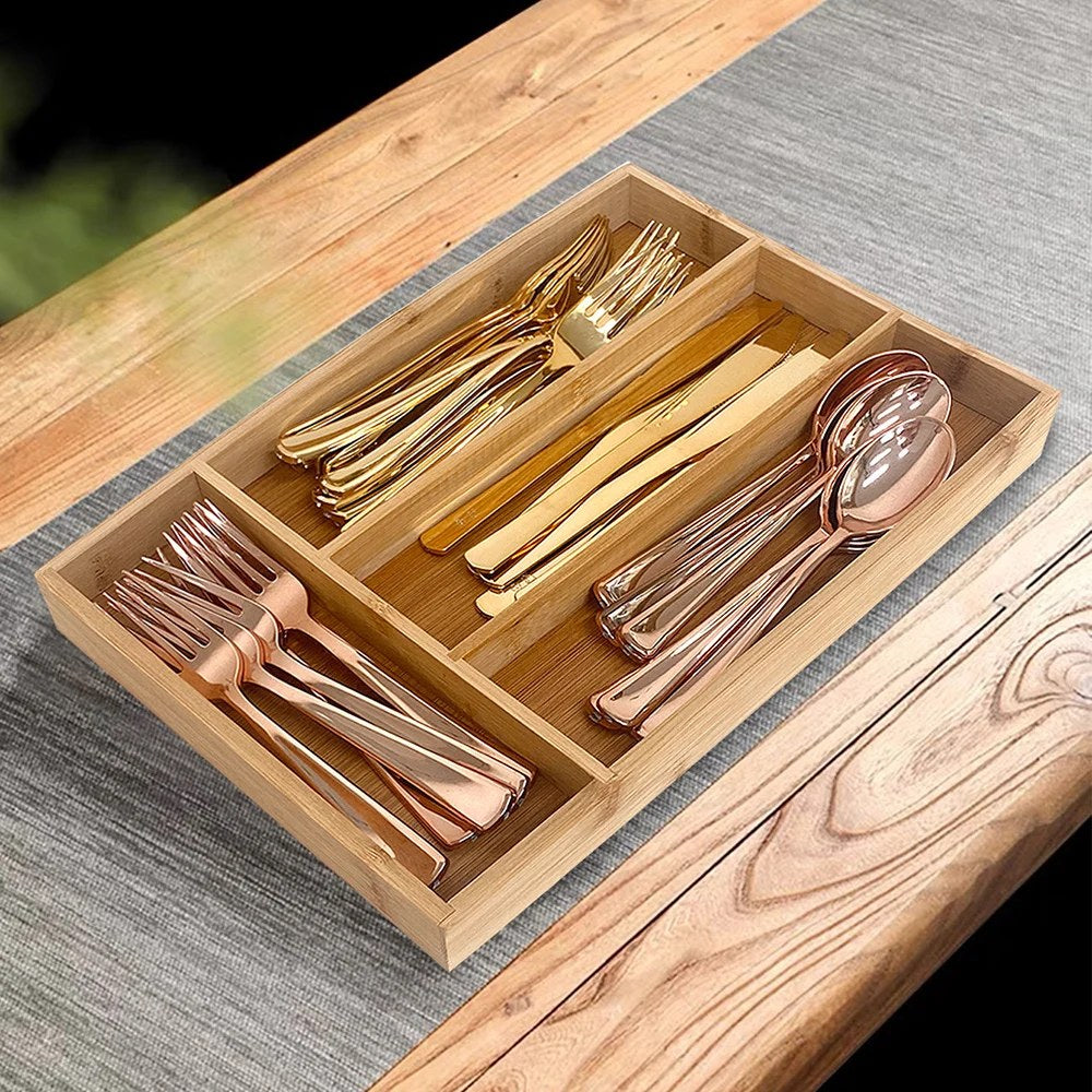 Portaposate da cassetto in bambù con quattro scomparti e posate dorate su un tavolo di legno