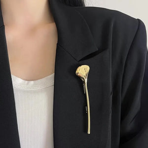 Spilla color oro a foglia di ginkgo appuntata in verticale su una giacca nera