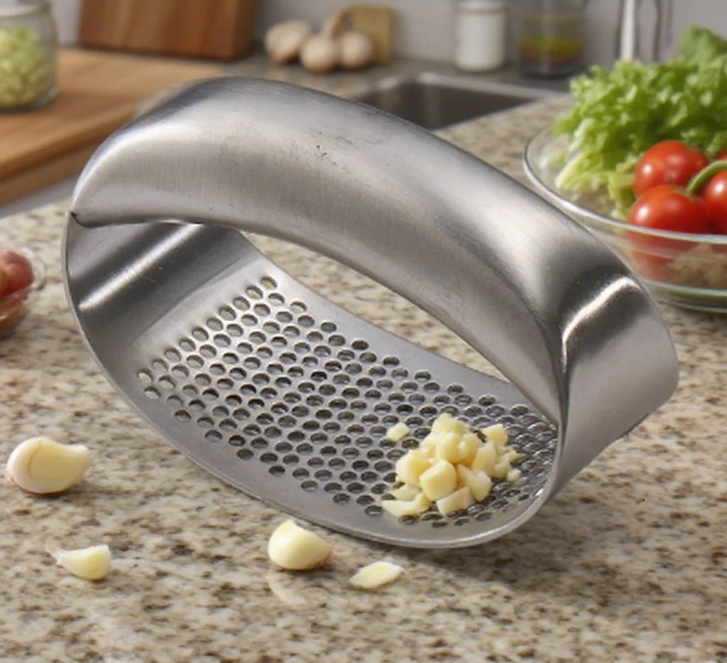 Spremiaglio curvo in acciaio inox con aglio schiacciato su un piano di lavoro della cucina