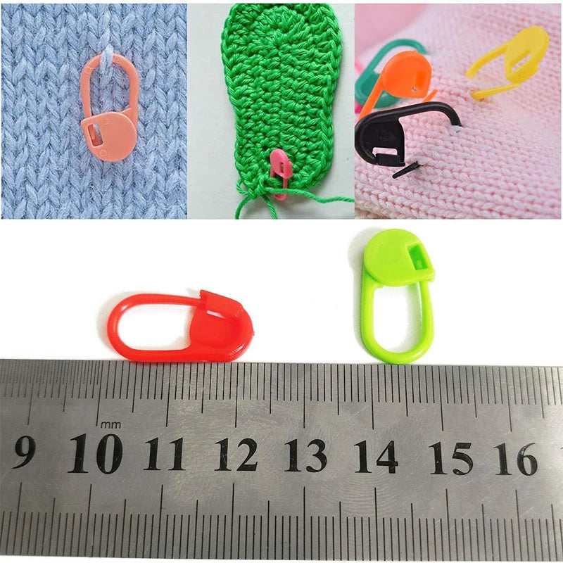 Due marcapunti sopra un righello, lunghi circa 2 cm, e marcapunti su lavori a maglia e all'uncinetto