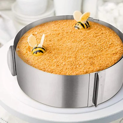 Anello per torte in acciaio inox intorno a una torta su un'alzata, con la giunzione e le due prese in vista