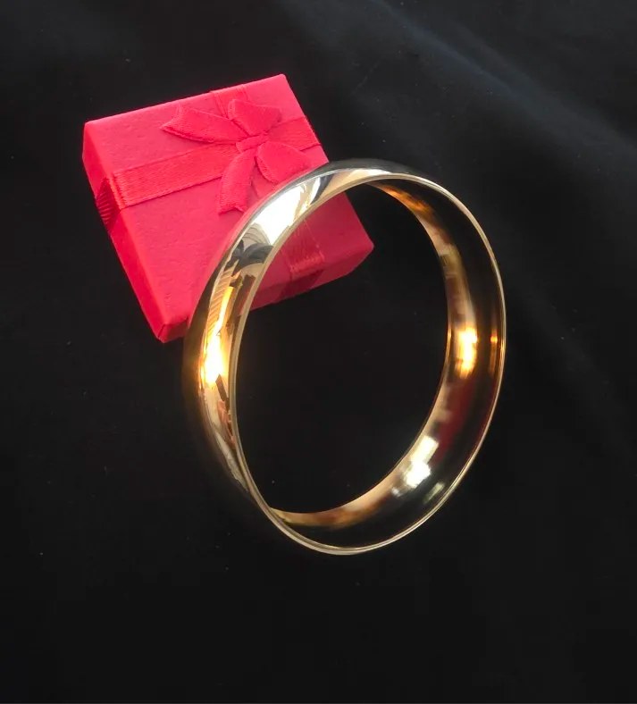 Foto di un cliente: bracciale rigido color oro e una piccola scatola rossa su un tessuto nero