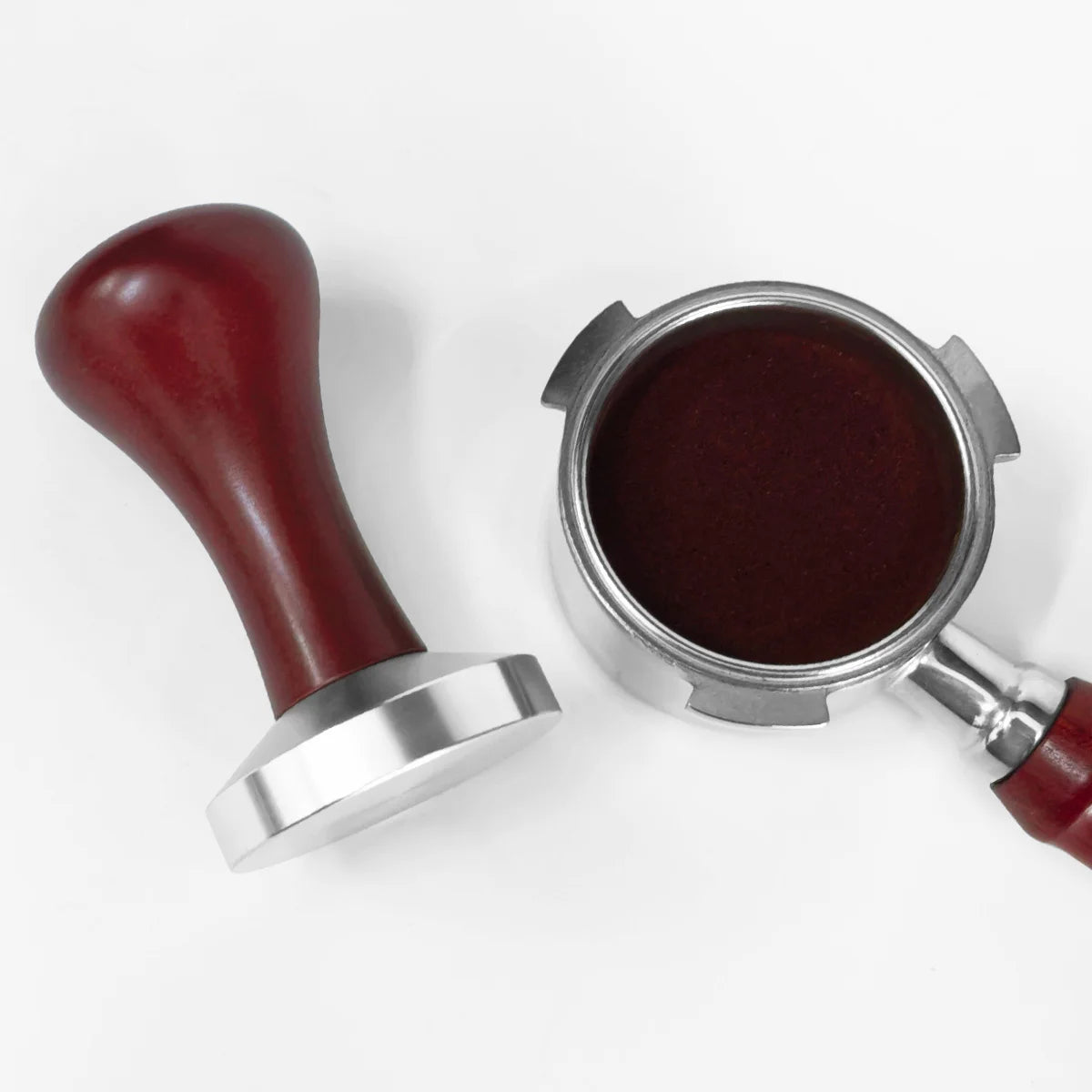 Il pressino appoggiato accanto a un portafiltro con il caffè pressato