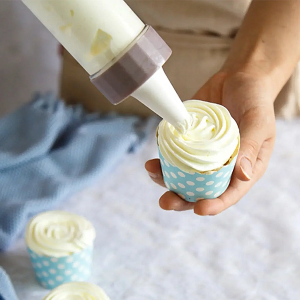 La sparabiscotti con un beccuccio mentre decora un cupcake con la crema
