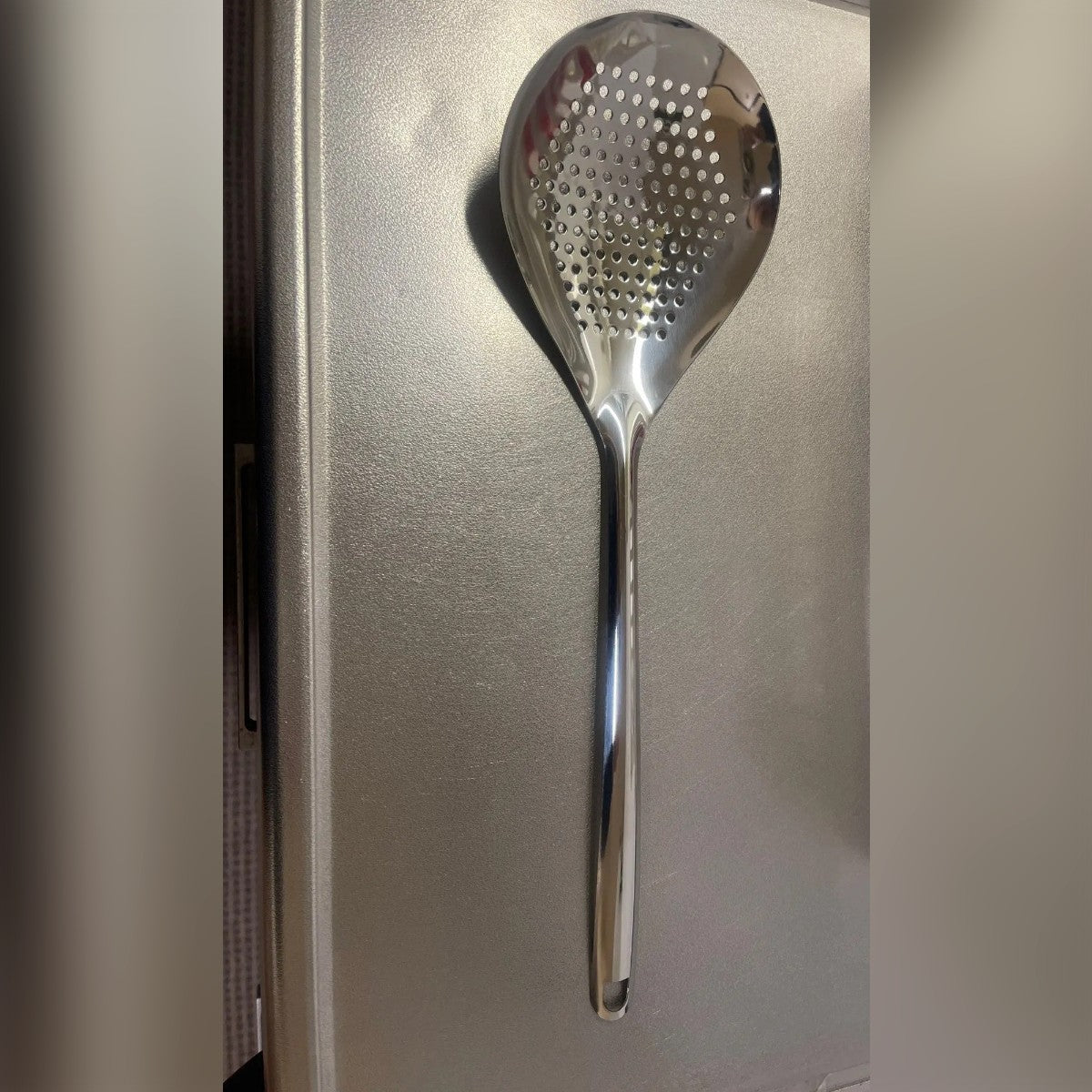 Foto di un acquirente: la schiumarola su un piano di lavoro, con coppa larga a fori tondi e manico lungo