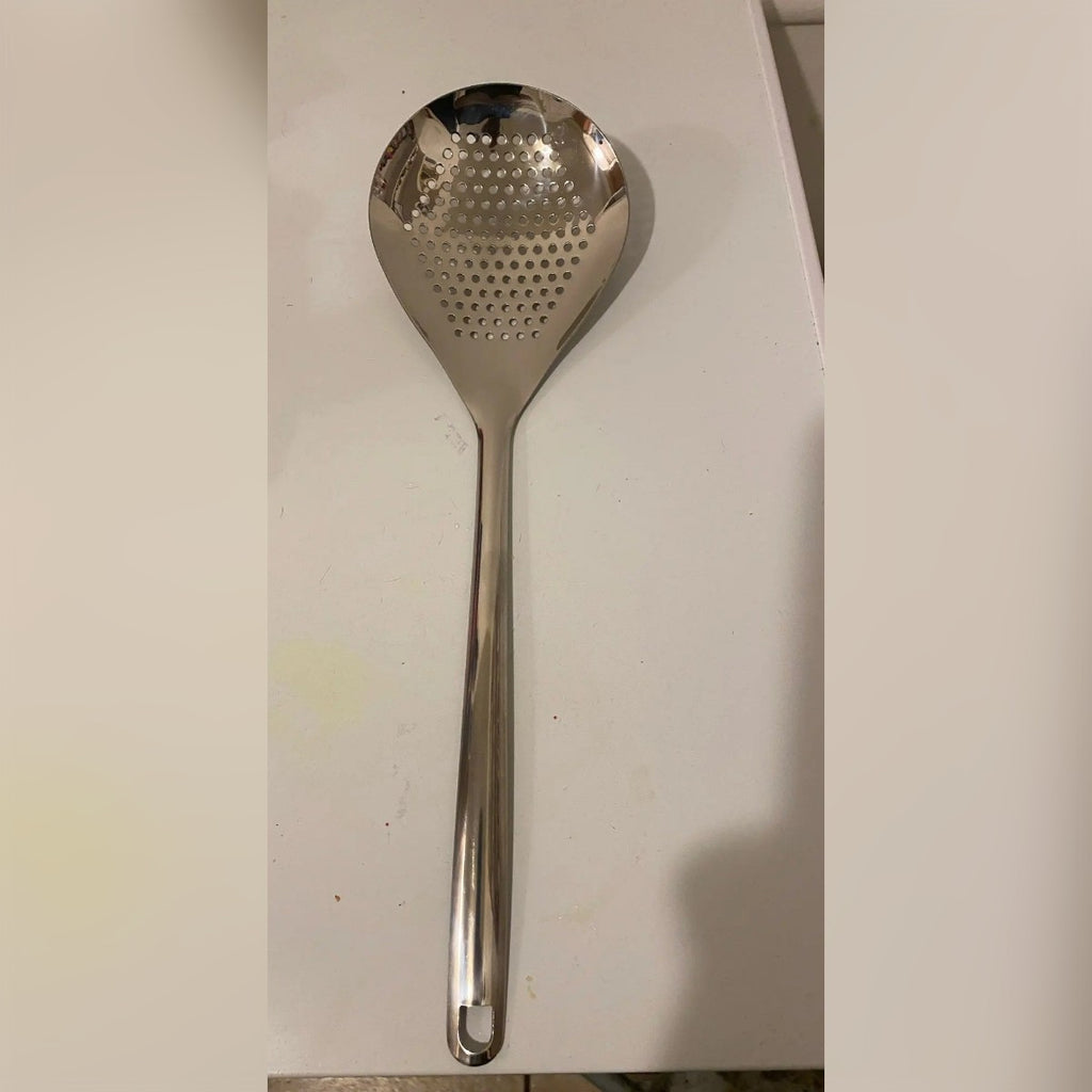 Foto di un acquirente: la schiumarola in acciaio inox su un piano di lavoro bianco