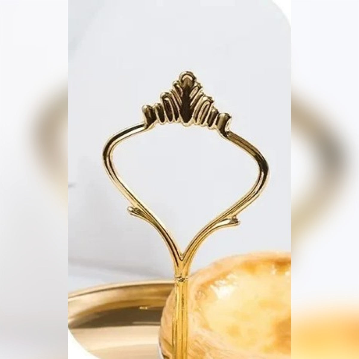 Il manico a forma di corona in metallo color oro in cima all'alzatina
