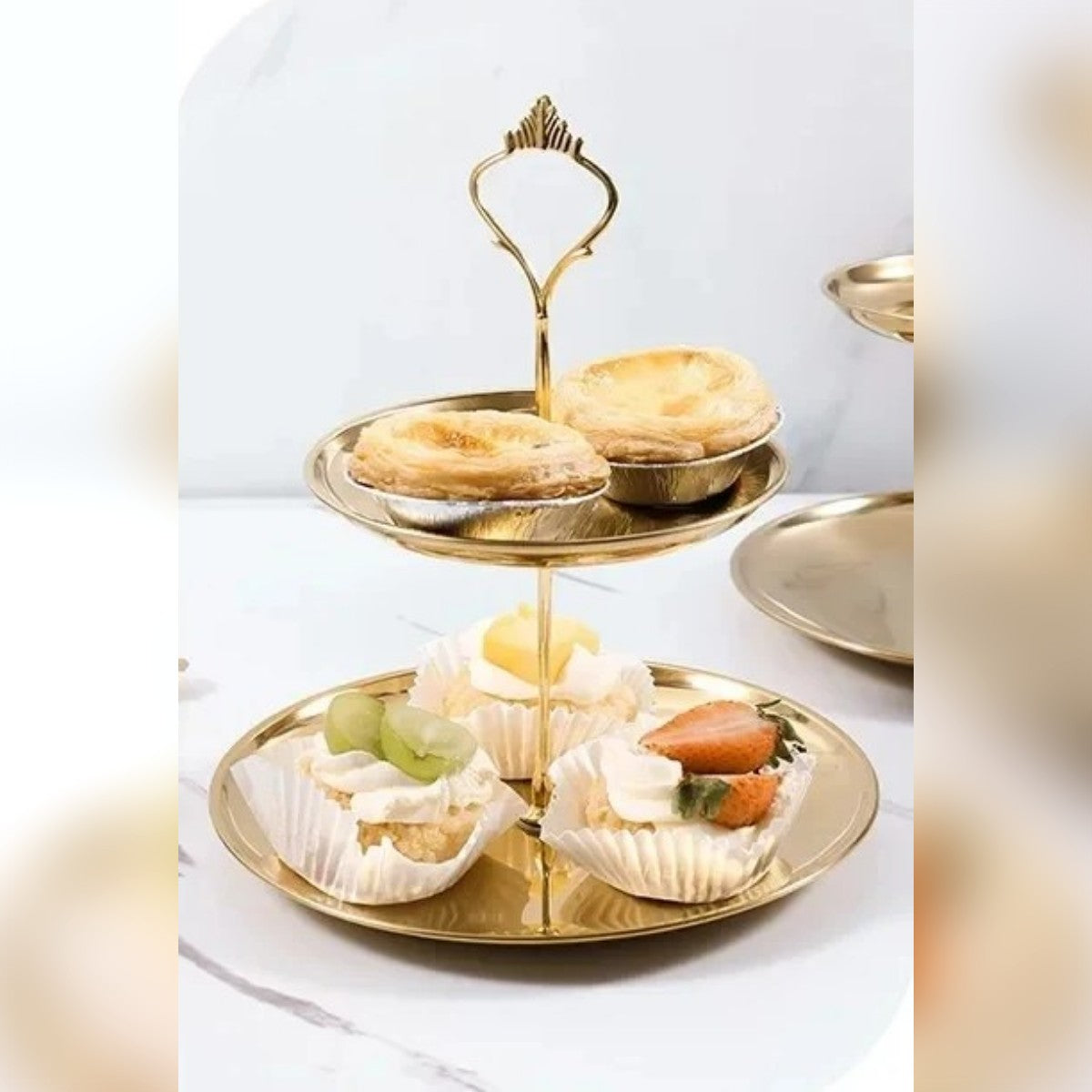 Alzatina a 2 piani con crostatine e pasticcini su un tavolo chiaro