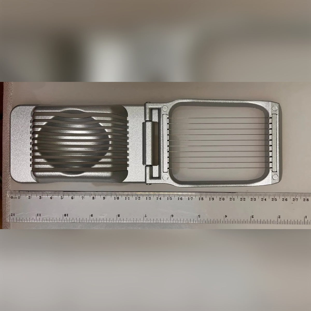 Foto di un acquirente: il taglia uova aperto accanto a un righello, circa 25,5 cm