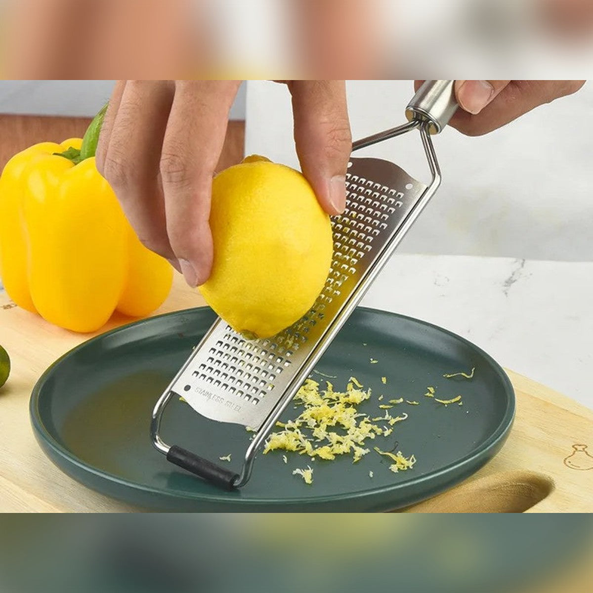 Scorza di limone grattugiata finemente su un piatto accanto alla grattugia