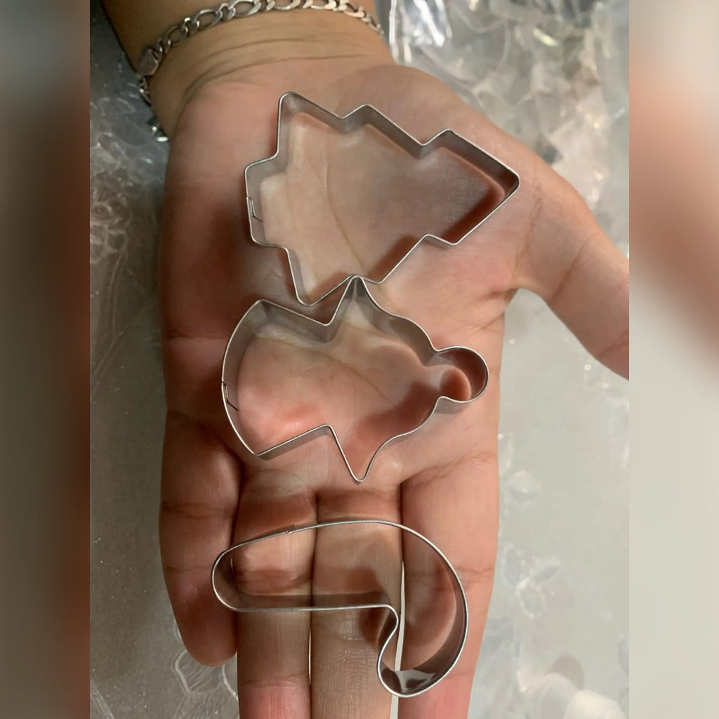 Foto di un acquirente: tre formine – albero, angelo e bastoncino di zucchero – nel palmo di una mano