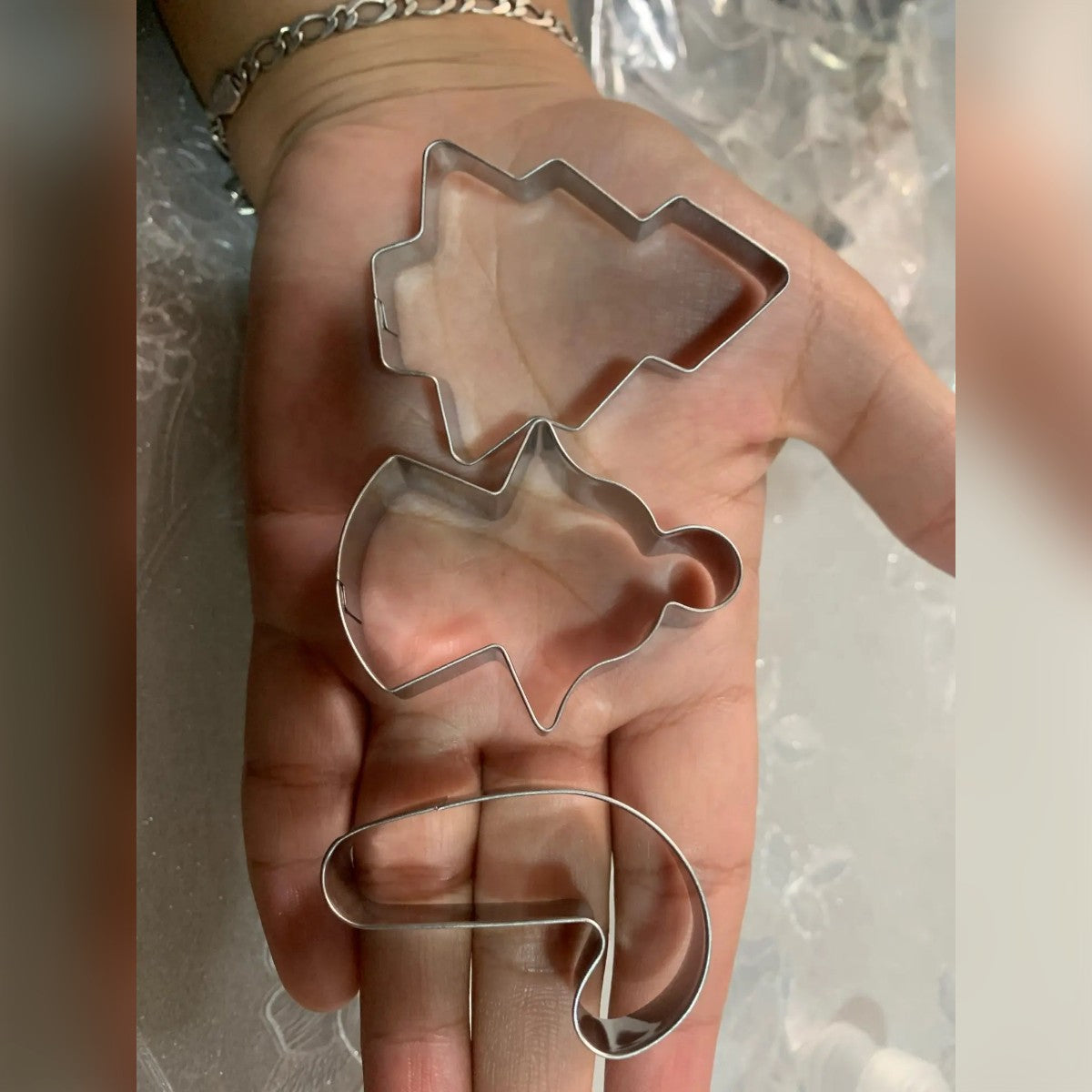 Foto di un acquirente: tre formine – albero, angelo e bastoncino di zucchero – nel palmo di una mano