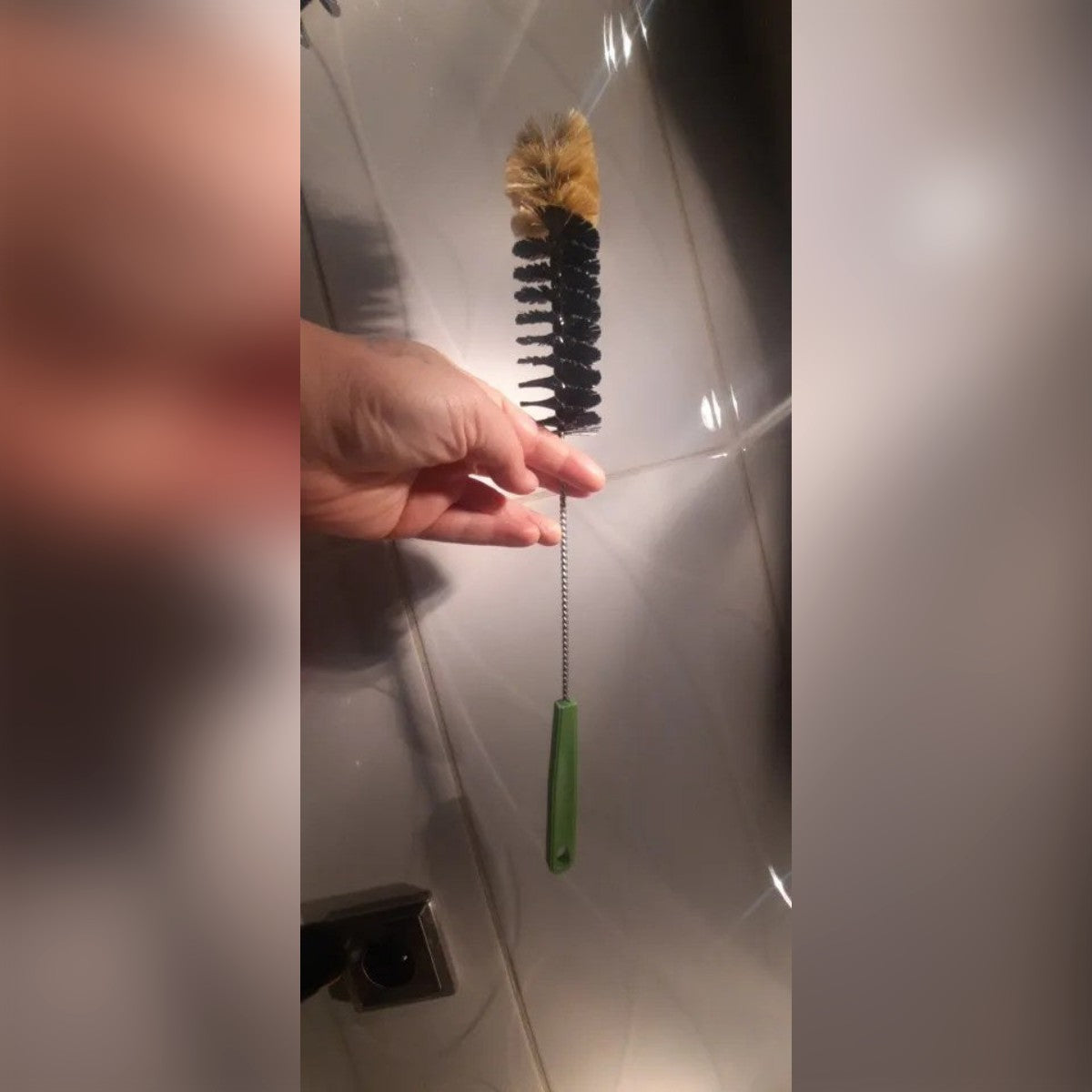 Foto di un acquirente: lo scovolino tenuto in mano, con le setole chiare sulla punta e il manico verde