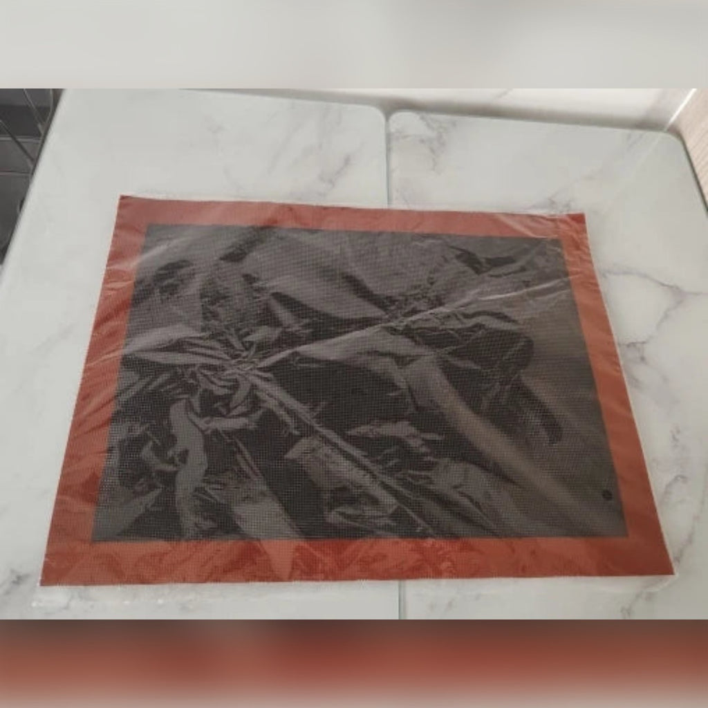Foto di un acquirente: il tappetino forato nella sua busta trasparente su un tavolo di marmo