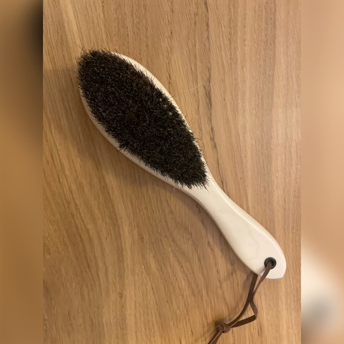 Foto di un acquirente: la spazzola per vestiti su un tavolo di legno, con le setole scure in crine di cavallo