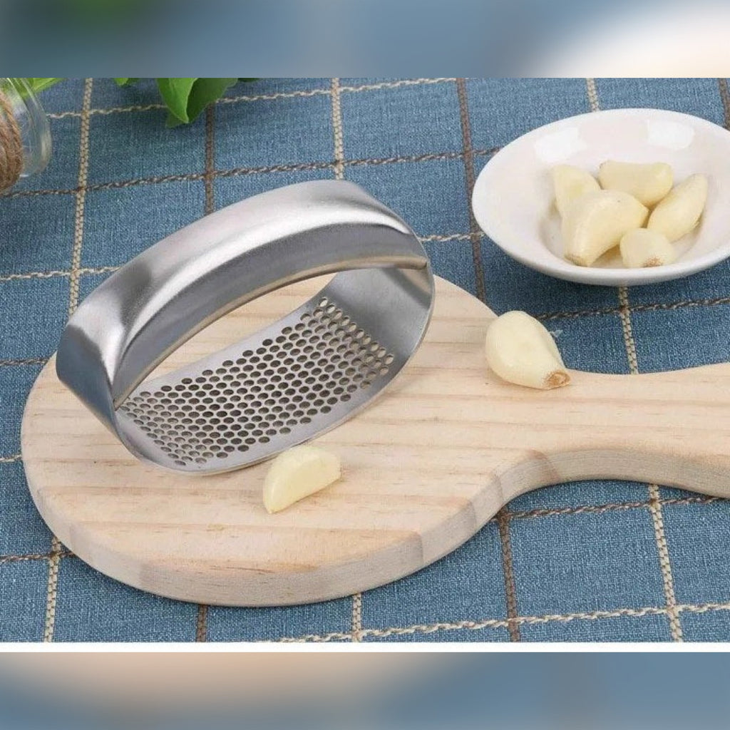 Lo spremiaglio su un tagliere di legno con spicchi d'aglio sbucciati
