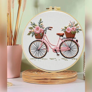 Kit ricamo con bicicletta e cesti di fiori – il ricamo finito nel telaio su una mensola, foto del fornitore