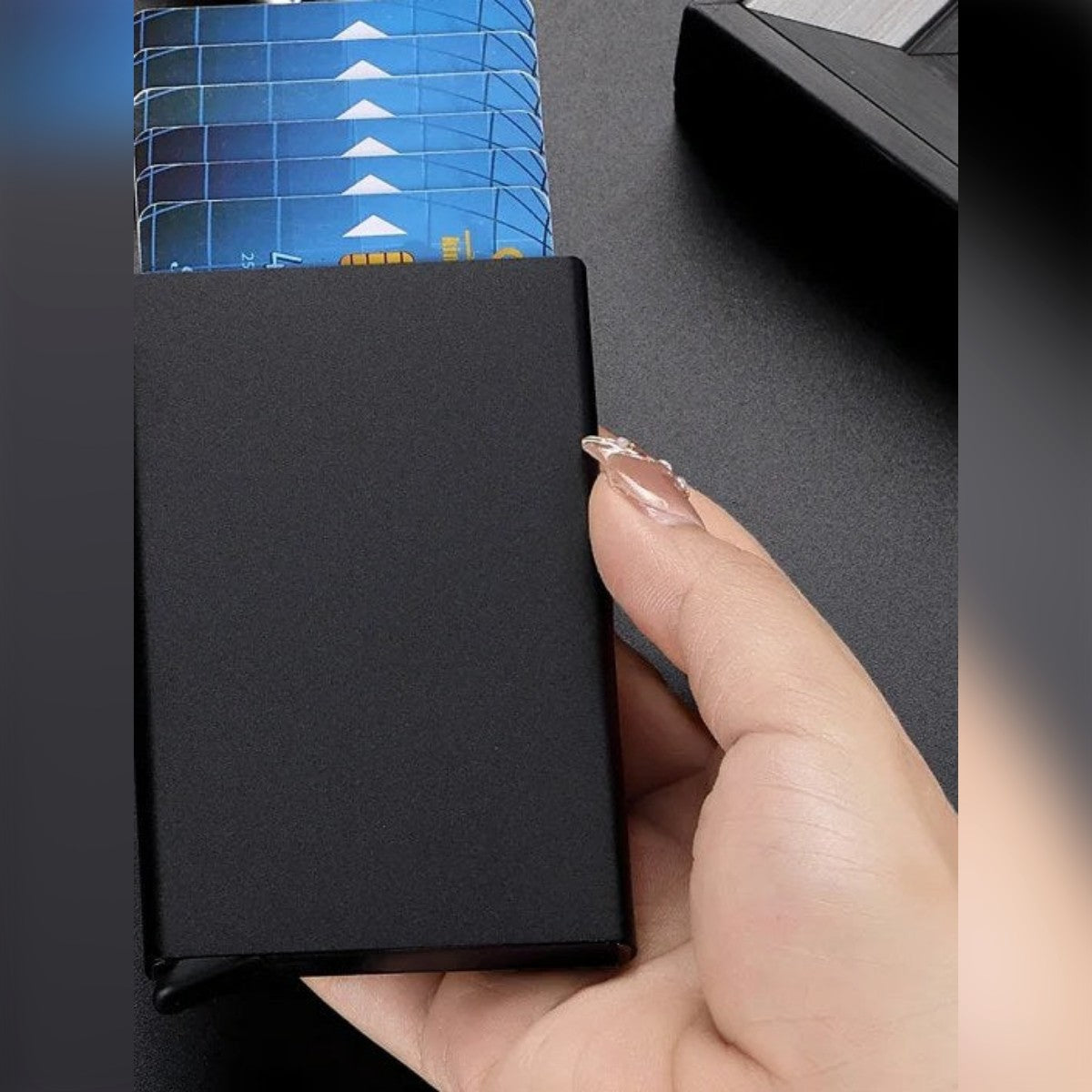 Portacarte nero in mano, con le carte uscite a scalare dall'apertura in alto