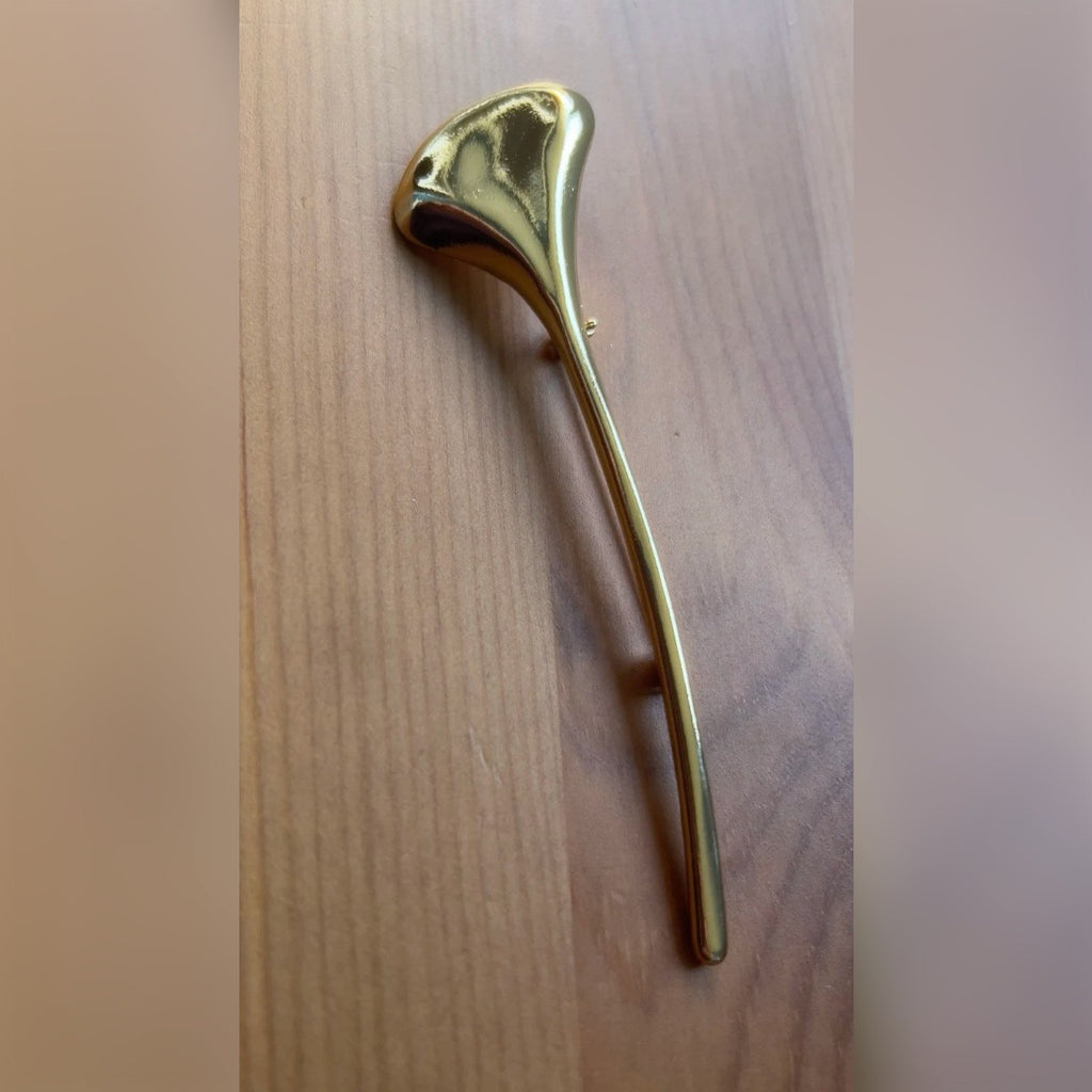 Foto di un cliente: la spilla color oro su un tavolo di legno