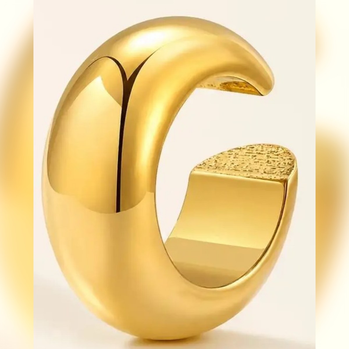 Ear cuff color oro su fondo chiaro, a forma di C con superficie bombata