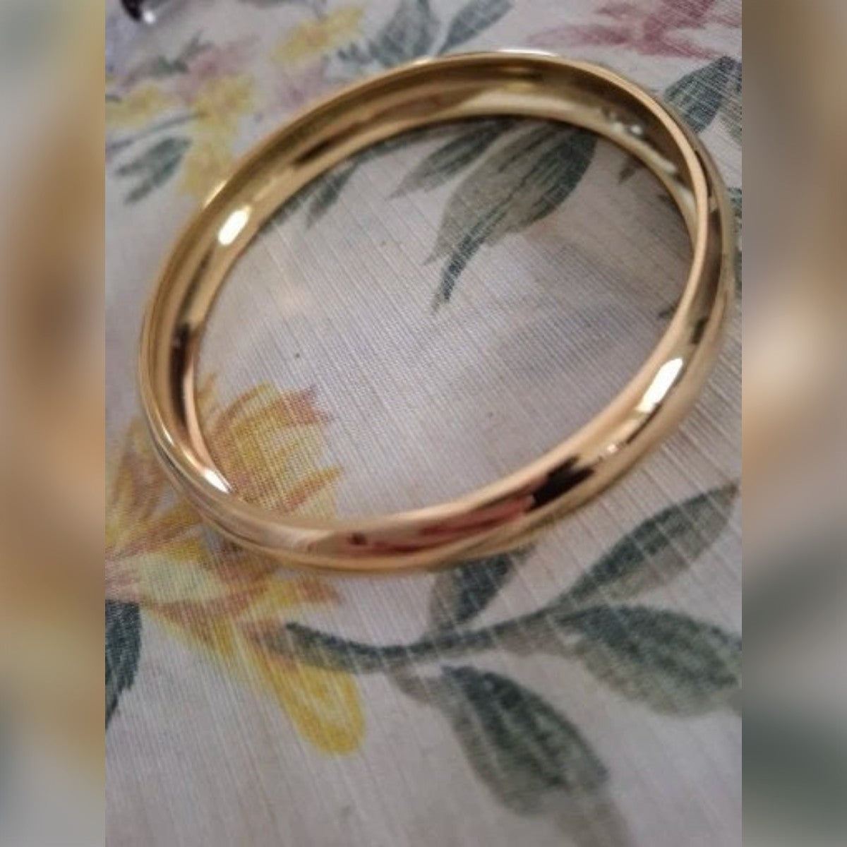 Foto di un cliente: bracciale rigido color oro su una tovaglia a fiori