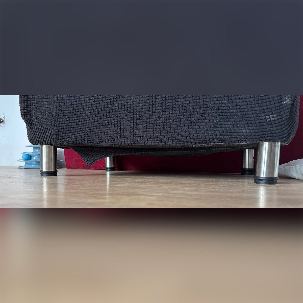 Foto di un cliente: i piedini sotto un divano su un pavimento in laminato – nella foto la versione da 10 cm