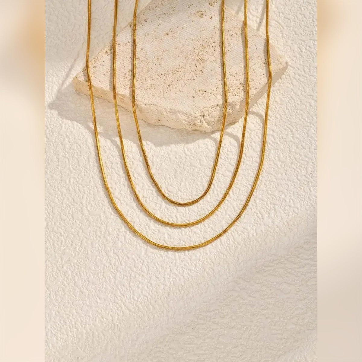Tre catene a serpente color oro di lunghezze diverse su una pietra – vendiamo una sola collana da 40 cm