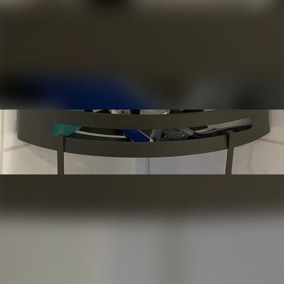 Foto di un cliente: il bordo della mensola grigia con i due ganci nell'angolo della doccia