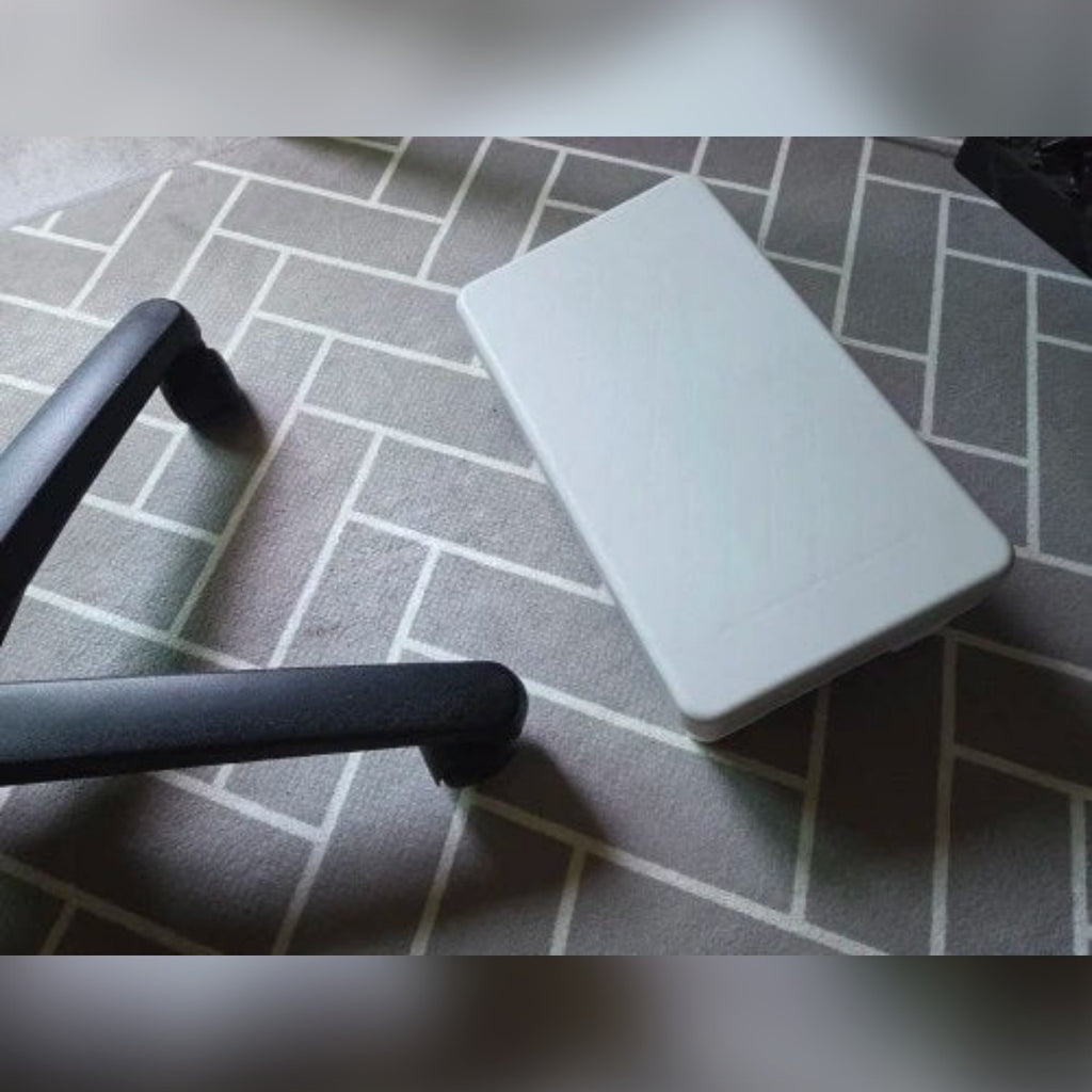 Foto di un cliente: il poggiapiedi grigio sul tappeto, accanto alle ruote della sedia da ufficio