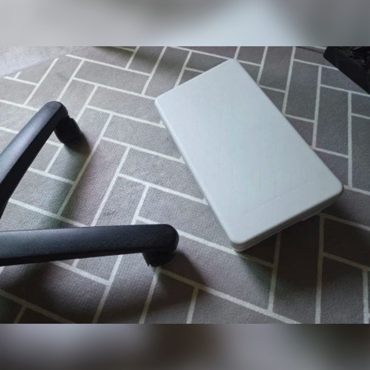 Foto di un cliente: il poggiapiedi grigio sul tappeto, accanto alle ruote della sedia da ufficio