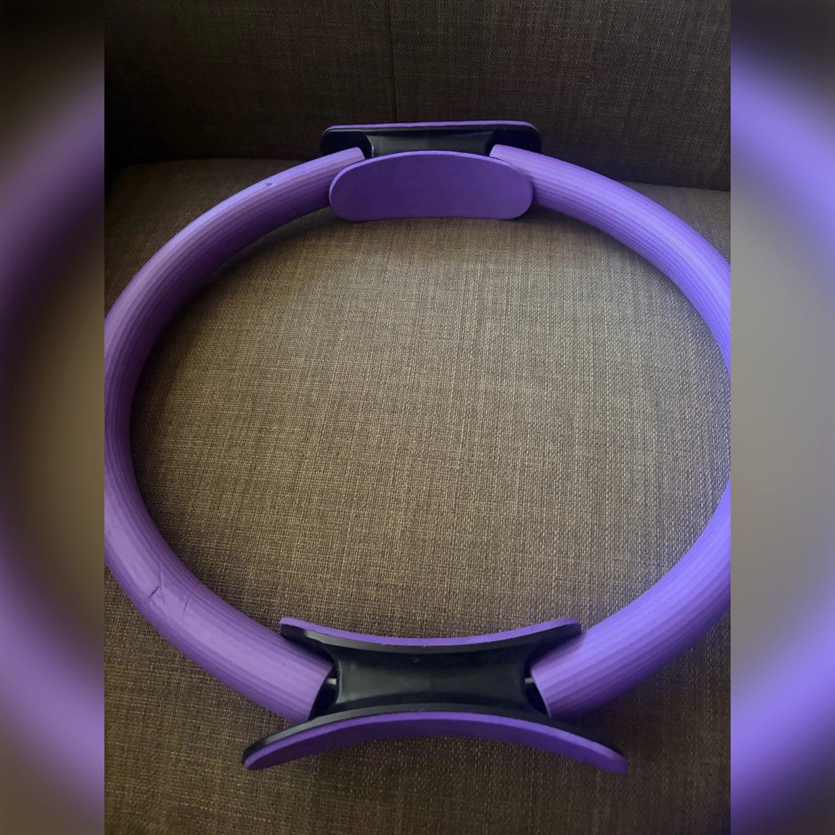 Foto di un cliente: pilates ring viola sul divano, con un'impugnatura in alto e una in basso