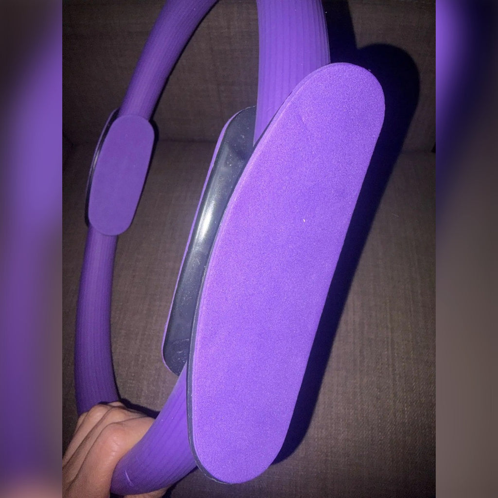 Foto di un cliente: l'impugnatura del pilates ring da vicino, imbottitura viola e cerchio rigato in mano