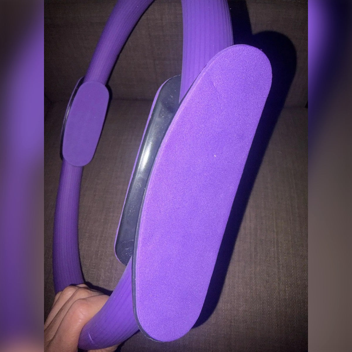 Foto di un cliente: l'impugnatura del pilates ring da vicino, imbottitura viola e cerchio rigato in mano