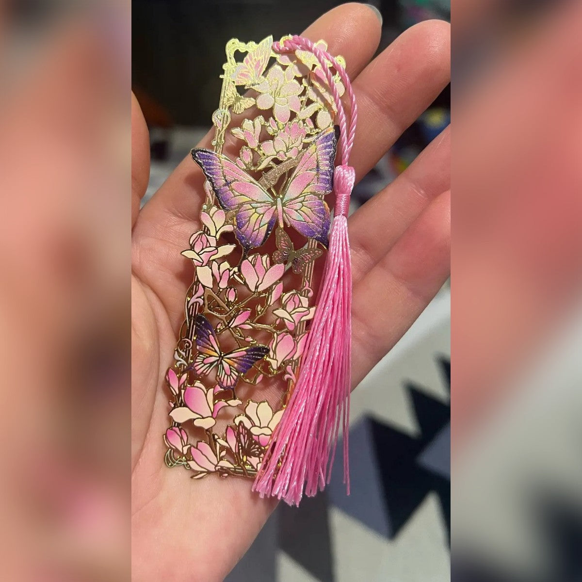 Segnalibro in metallo in mano: magnolie rosa, farfalle viola e nappina rosa (foto di un cliente)