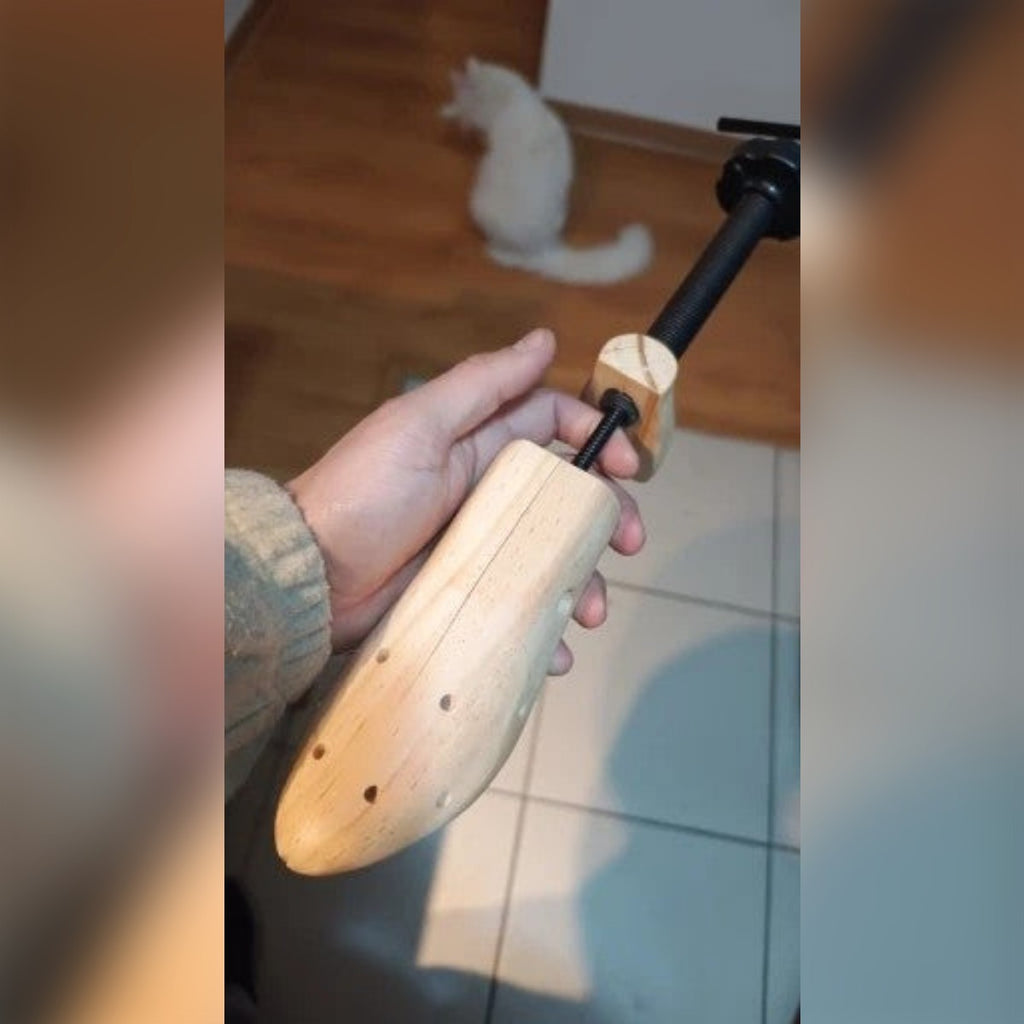 Foto di un cliente: allarga scarpe in legno tenuto in mano, con i fori sulla punta e la vite nera