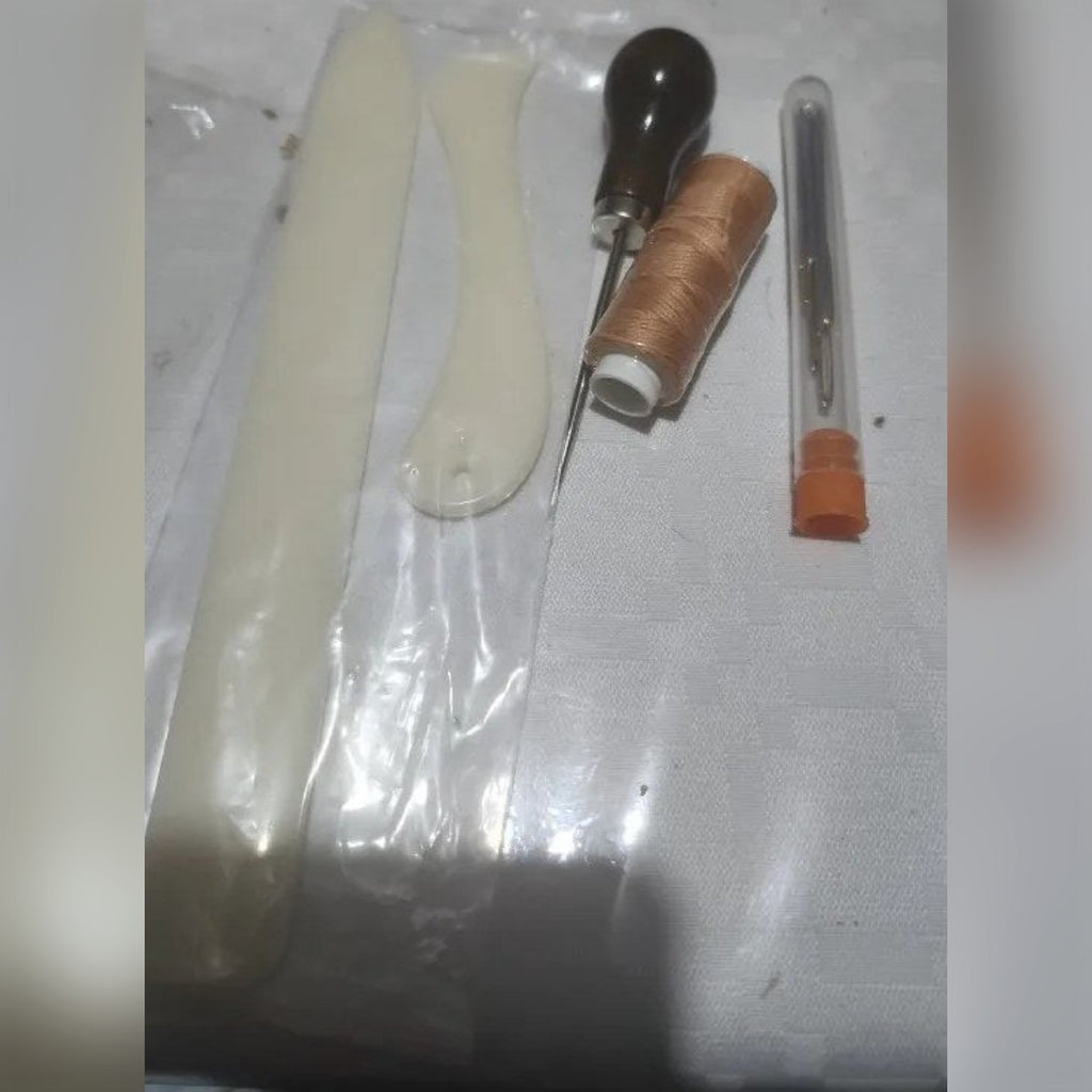Foto di un cliente: le due stecche, il punteruolo, il rocchetto di filo cerato e il tubetto con gli aghi sul tavolo
