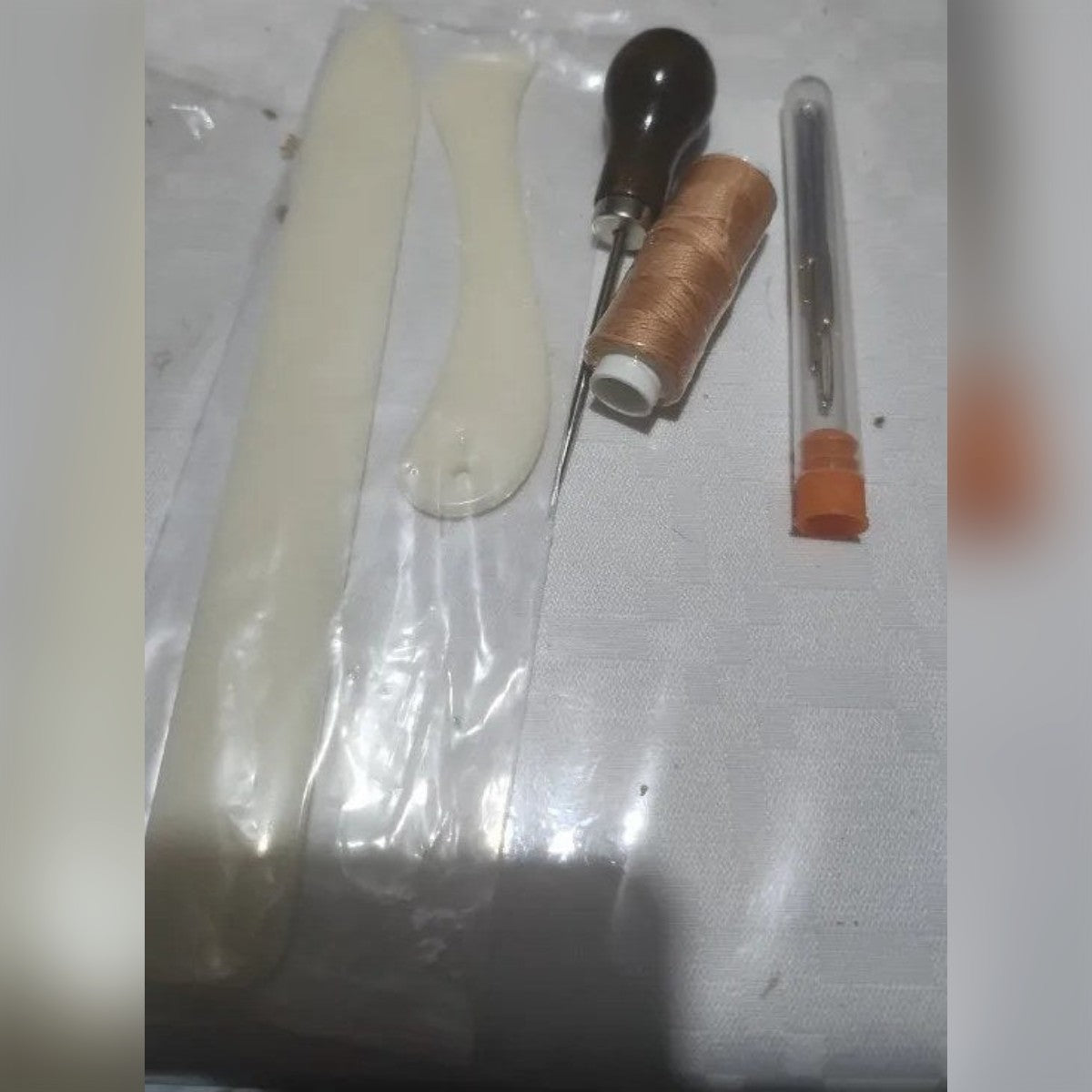 Foto di un cliente: le due stecche, il punteruolo, il rocchetto di filo cerato e il tubetto con gli aghi sul tavolo