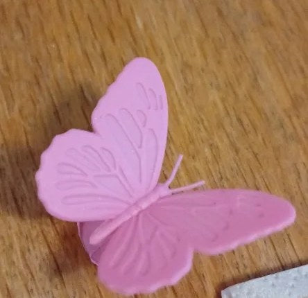Foto di un cliente: una farfalla segnabicchiere rosa su un tavolo di legno
