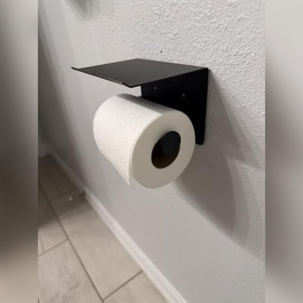 Foto di un acquirente: il porta rotolo nero con mensola su una parete chiara, con un rotolo sul braccio