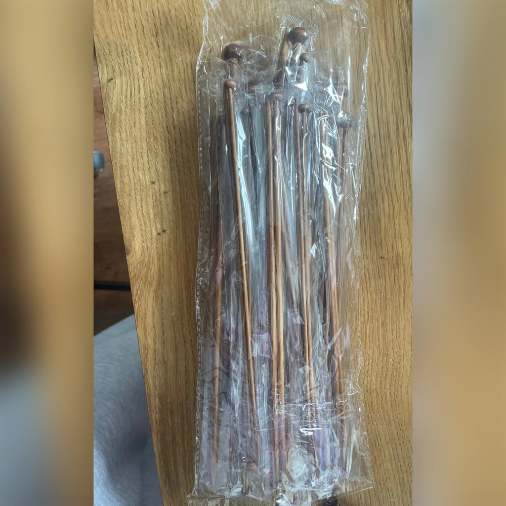 Foto di un acquirente: i ferri da maglia con pomolo, a coppie nelle bustine, su un tavolo di legno