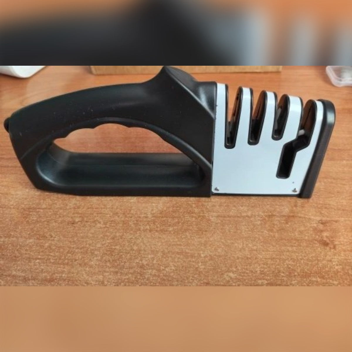 Foto di un acquirente: l'affilacoltelli ricevuto, visto dal lato dell'impugnatura, su un tavolo di legno