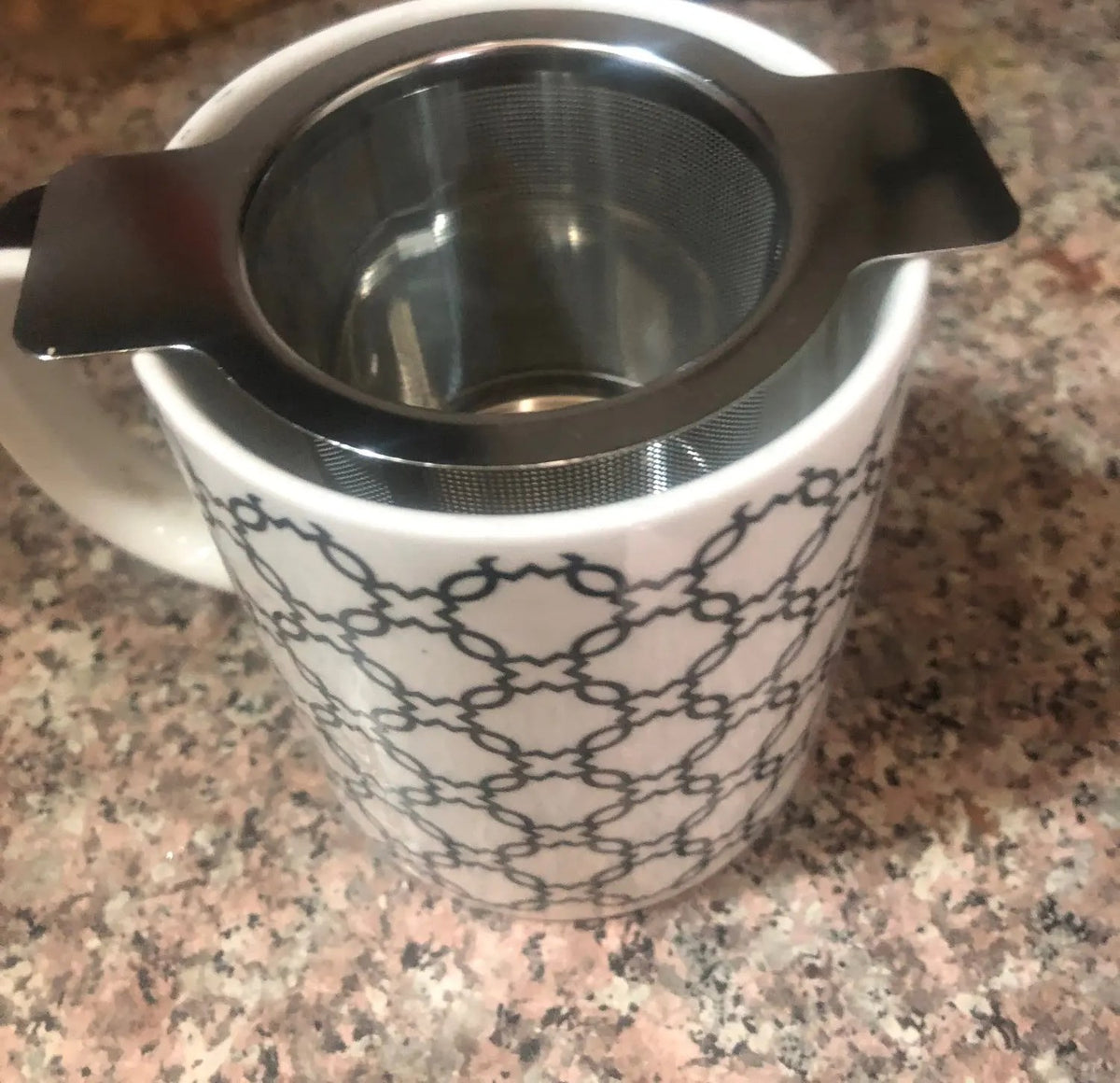 Foto di un acquirente: il filtro per tè con i manici appoggiati sul bordo di una tazza decorata
