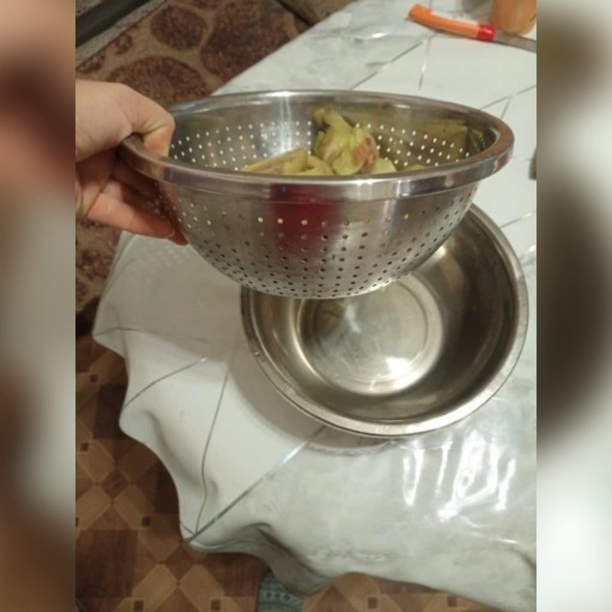 Foto di un acquirente: lo scolapasta sollevato sopra la ciotola dopo il risciacquo