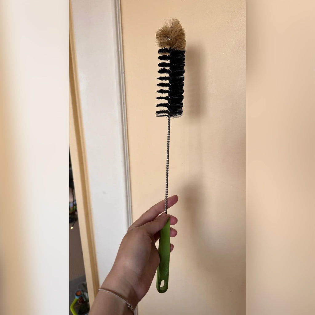 Foto di un acquirente: lo scovolino intero tenuto in mano, con manico verde, stelo ritorto e testa di setole