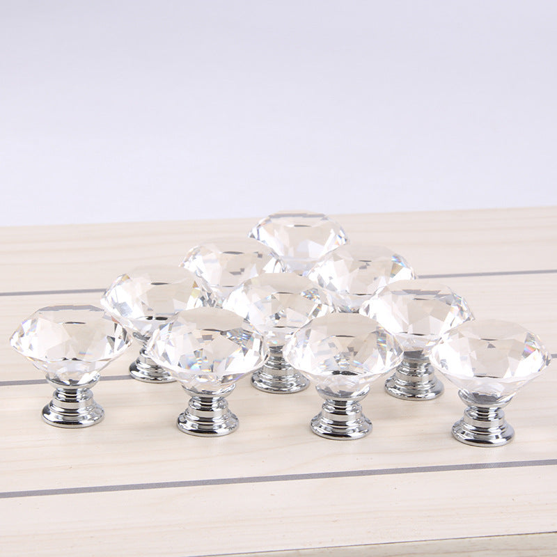 Dieci pomelli in vetro trasparente con base color argento su un piano di legno chiaro